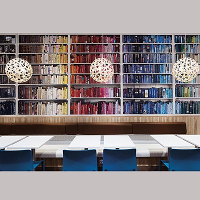 Interior showing a wall of colourful books, lamps and tables. Interior at a MAX restaurant. Photo